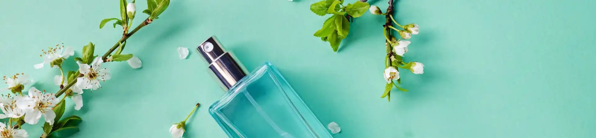 Flacon cosmétique entouré de fleurs sur fond turquoise